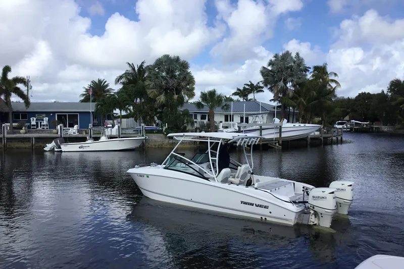 Slide: The Image of 2020 Twin Vee 240 DC GF boat cruising on a calm waterway with palm trees in the background. - 9