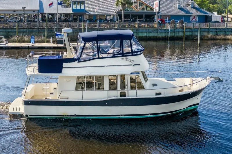 Slide: The Image of 2009 Mainship 40 Expedition yacht cruising near a waterfront restaurant. - 4