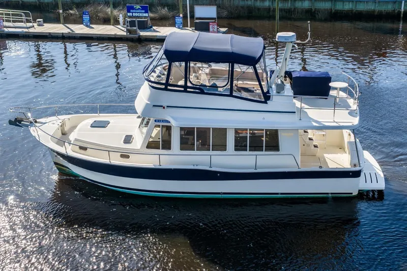 The Image of 2009 Mainship 40 Expedition yacht with blue canopy, docked on calm water. - 1