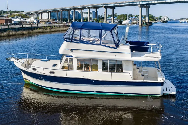 Slide: The Image of 2009 Mainship 40 Expedition yacht cruising on a calm river near a bridge. - 3