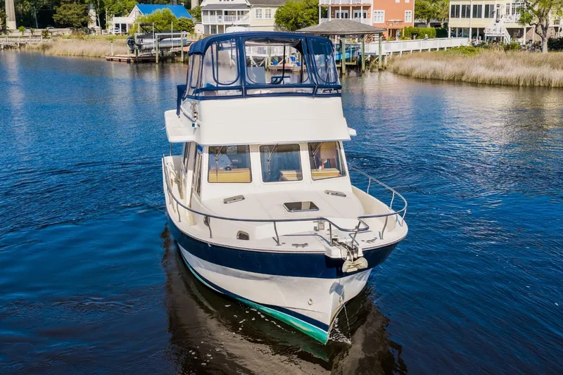 Slide: The Image of 2009 Mainship 40 Expedition yacht cruising on a serene waterway near waterfront homes. - 5