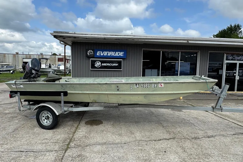 The Image of 1992 Weldcraft 1648 boat on trailer outside dealership, featuring Evinrude and Mercury signage. - 1