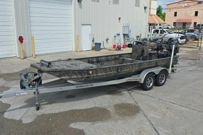 The Image of 2021 Prodrive 2060 boat on trailer, camo design, parked outside industrial building. - 1