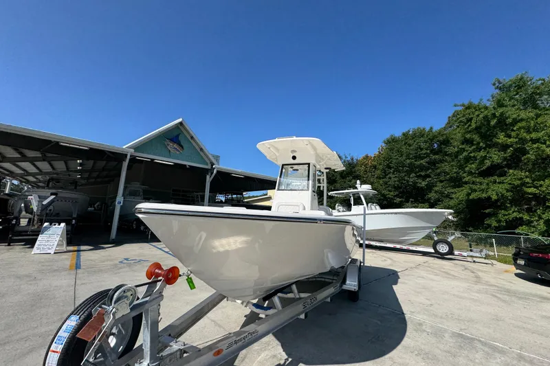 Slide: The Image of 2027 Sea Born LX22 Center Console boat on trailer at dealership under clear blue sky. - 4