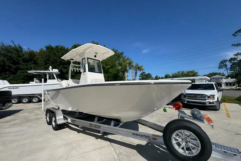 Slide: The Image of 2027 Sea Born LX22 Center Console boat on trailer, parked outdoors under clear blue sky. - 6