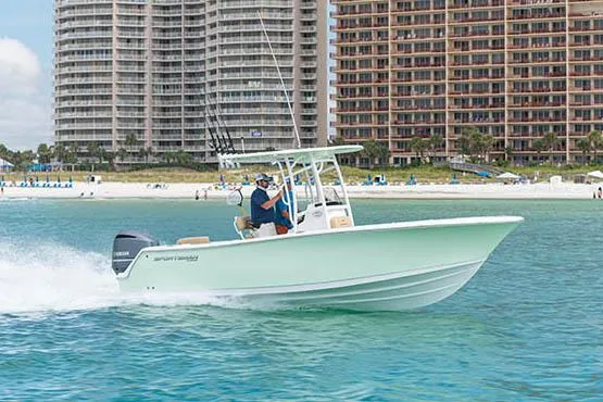 Slide: The Image of Manufacturer Provided Image: 2021 Sportsman Open 232 Center Console boat cruising near beachfront buildings. - 1