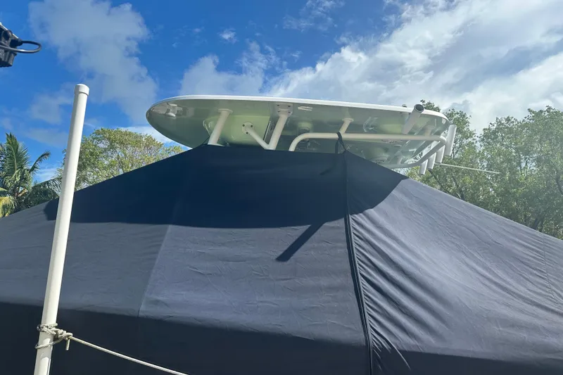 Slide: The Image of 2021 Sportsman Open 232 Center Console boat partially covered, with blue sky and trees in background. - 23
