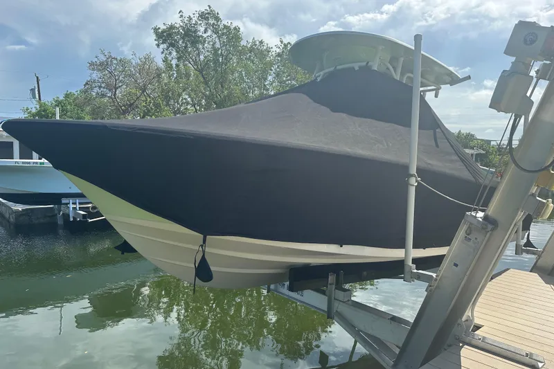Slide: The Image of 2021 Sportsman Open 232 Center Console boat covered and docked by the water. - 24