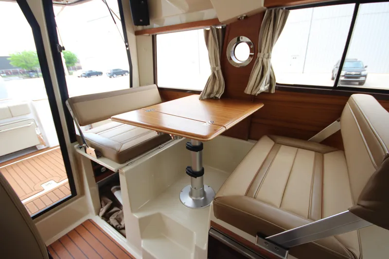 Slide: The Image of Interior of 2025 Ranger Tugs R-25, featuring a cozy dining area with wood accents. - 13