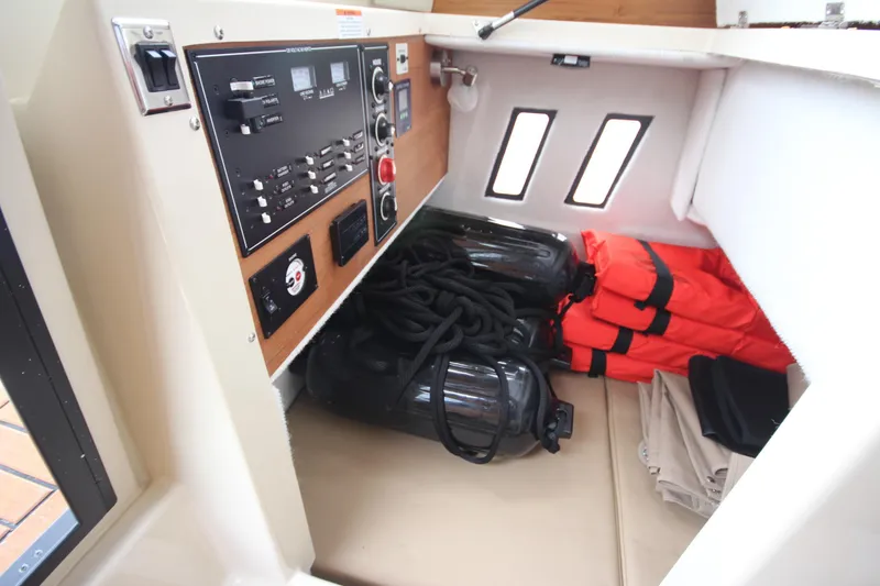 Slide: The Image of 2025 Ranger Tugs R-25 interior storage with life jackets, ropes, and control panel. - 16