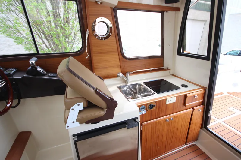 Slide: The Image of Interior of 2025 Ranger Tugs R-25 featuring compact kitchen with sink and stove. - 18