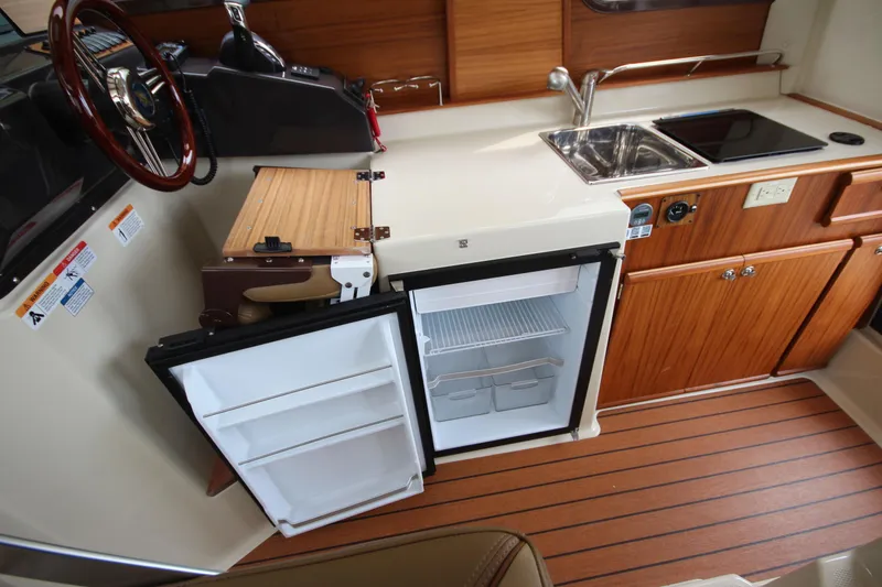 Slide: The Image of 2025 Ranger Tugs R-25 interior with kitchenette, featuring fridge, sink, and stove. - 20
