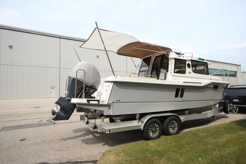 Slide: The Image of 2025 Ranger Tugs R-25 boat on trailer, parked near industrial building. - 3
