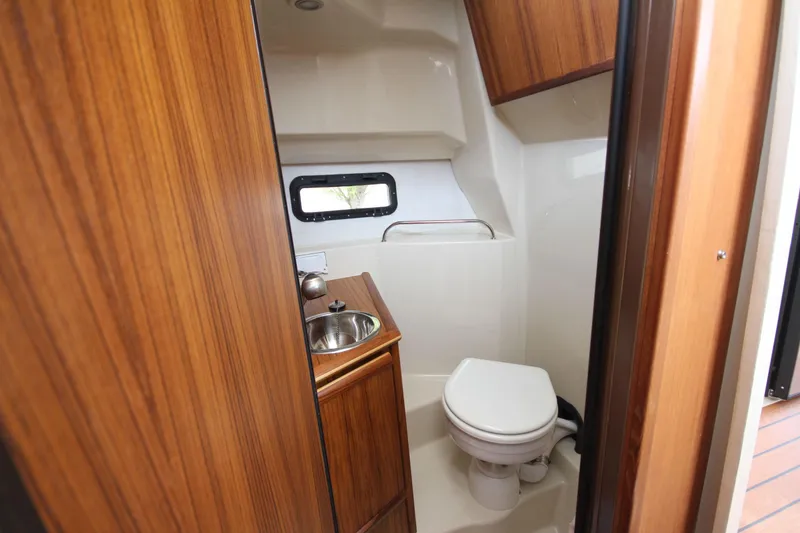 Slide: The Image of 2025 Ranger Tugs R-25 boat bathroom with wood accents and compact design. - 35