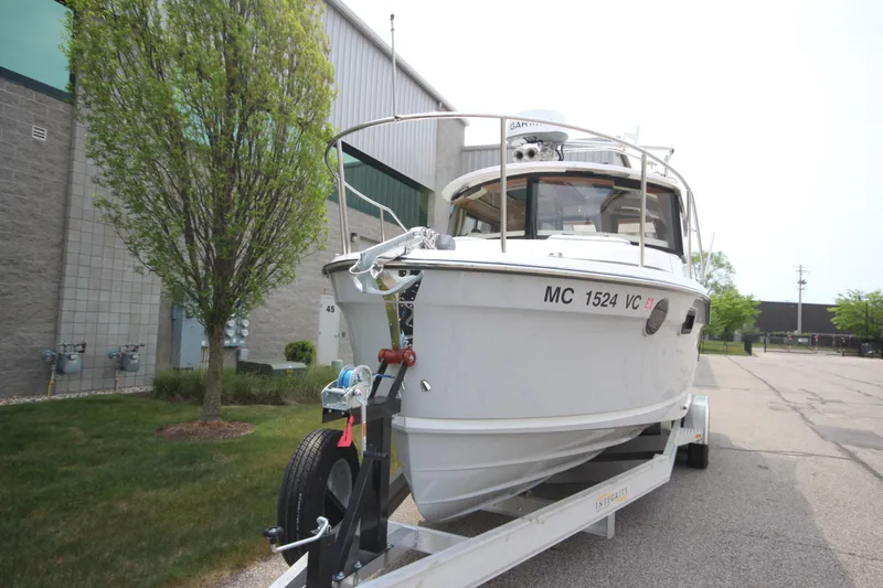 Slide: The Image of 2025 Ranger Tugs R-25 boat on trailer, parked outdoors near a building. - 4