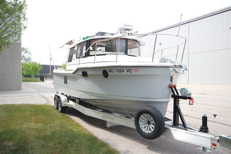 Slide: The Image of 2025 Ranger Tugs R-25 boat on trailer, parked outdoors near industrial building. - 5