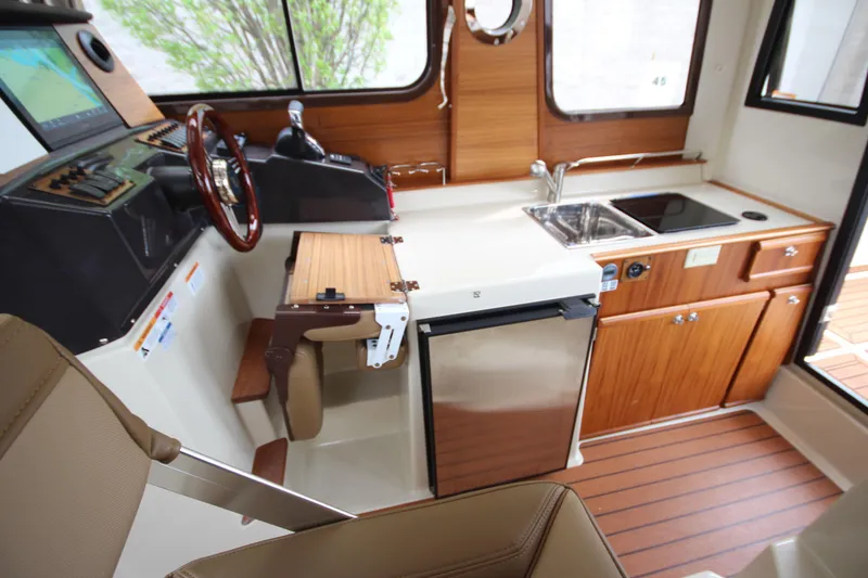 Slide: The Image of Interior of 2025 Ranger Tugs R-25, featuring helm, kitchenette, and wood accents. - 58