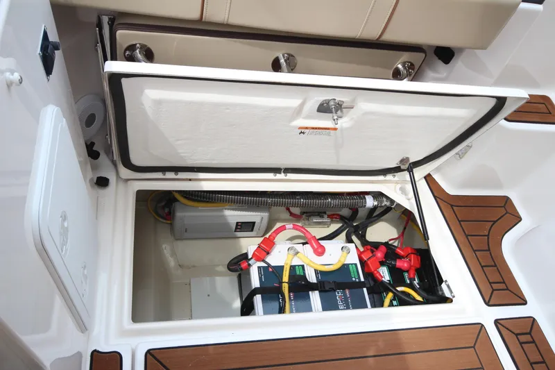 Slide: The Image of 2025 Ranger Tugs R-25 boat battery compartment with wiring and storage. - 9