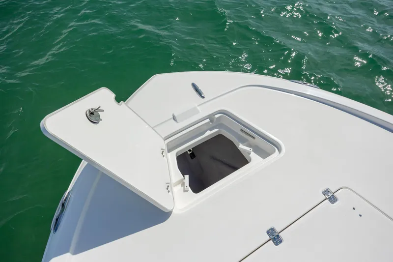 Slide: The Image of Open storage compartment on 2026 Caymas 281 HB boat deck, surrounded by green water. - 12