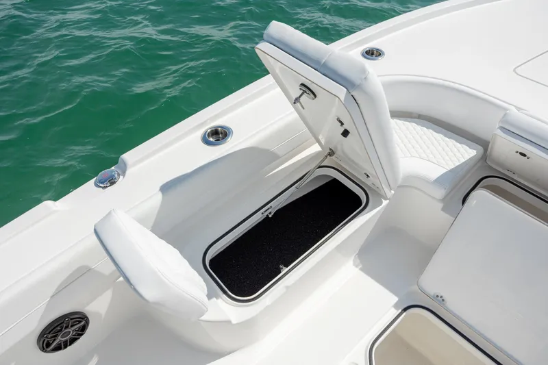 Slide: The Image of 2026 Caymas 281 HB boat with open storage compartment on deck, near turquoise water. - 15
