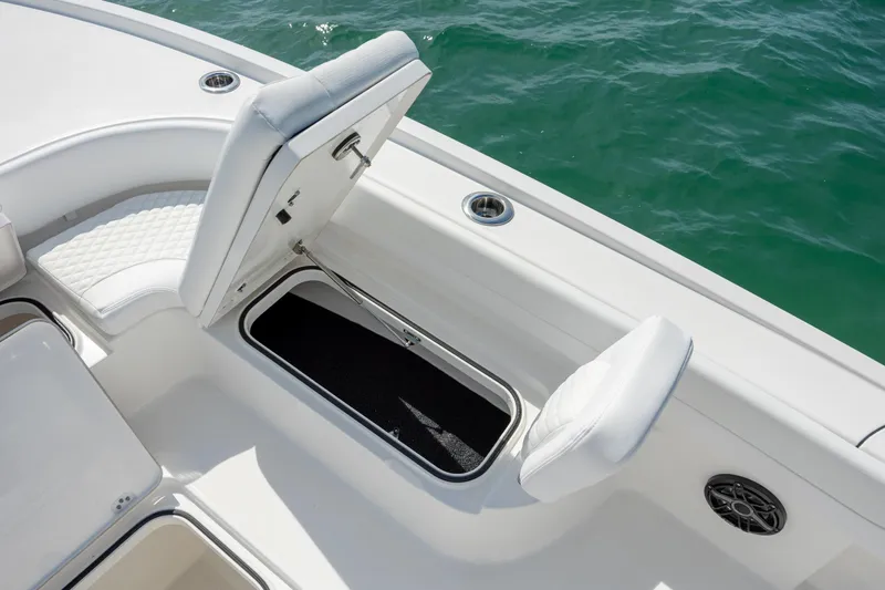 Slide: The Image of 2026 Caymas 281 HB boat with open storage compartment, white seating, and ocean backdrop. - 16