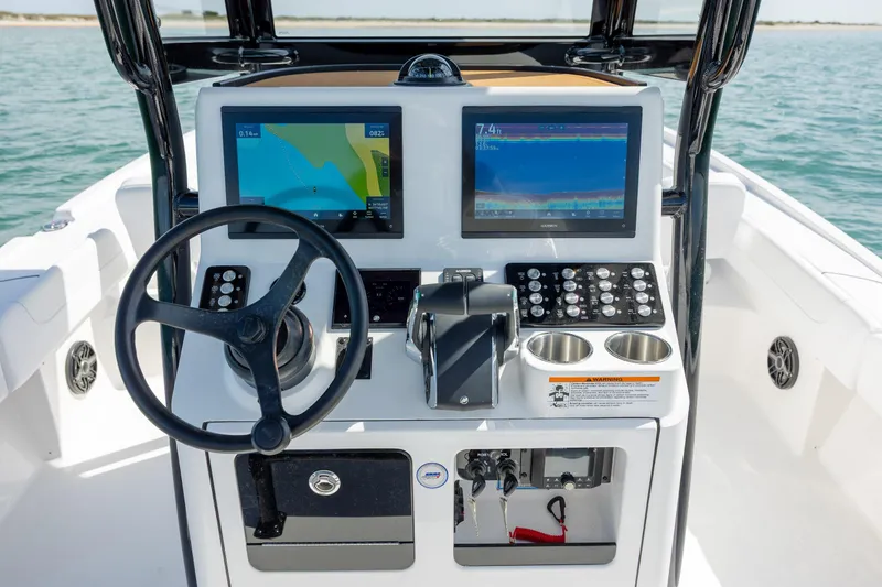 Slide: The Image of 2026 Caymas 281 HB boat dashboard with dual screens and steering wheel on open water. - 23