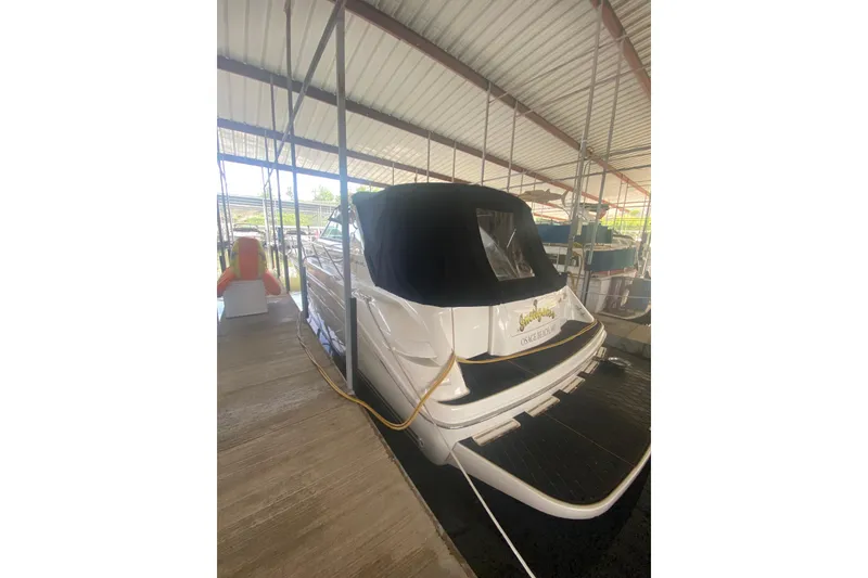 Slide: The Image of 1995 Sea Ray Sundancer 370 docked in covered marina, rear view with black cover. - 2