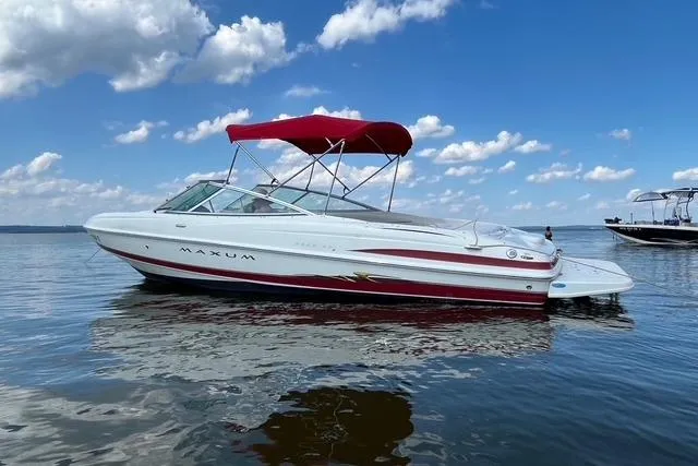 The Image of 2004 Maxum 2200 SR3 boat with red canopy on calm water under blue sky. - 0