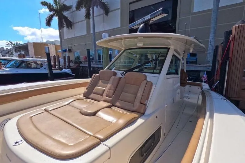 Slide: The Image of 2018 Scout 380 LXF boat with tan seating, docked near palm trees. - 10