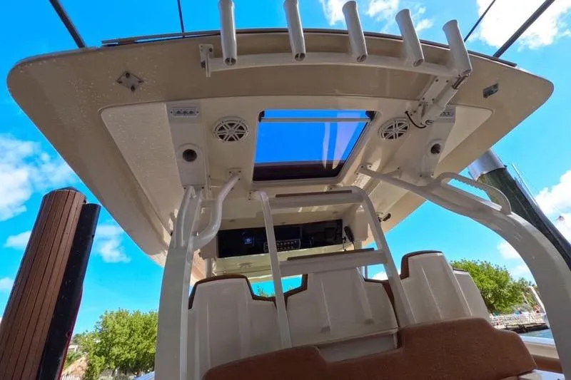 Slide: The Image of 2018 Scout 380 LXF boat interior with rod holders and speakers under a clear blue sky. - 11