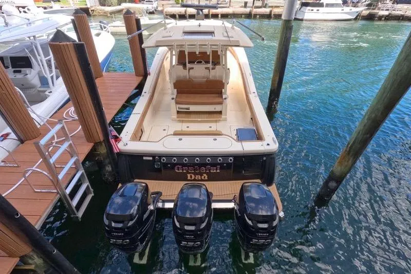 Slide: The Image of 2018 Scout 380 LXF boat docked with triple outboard engines. - 3
