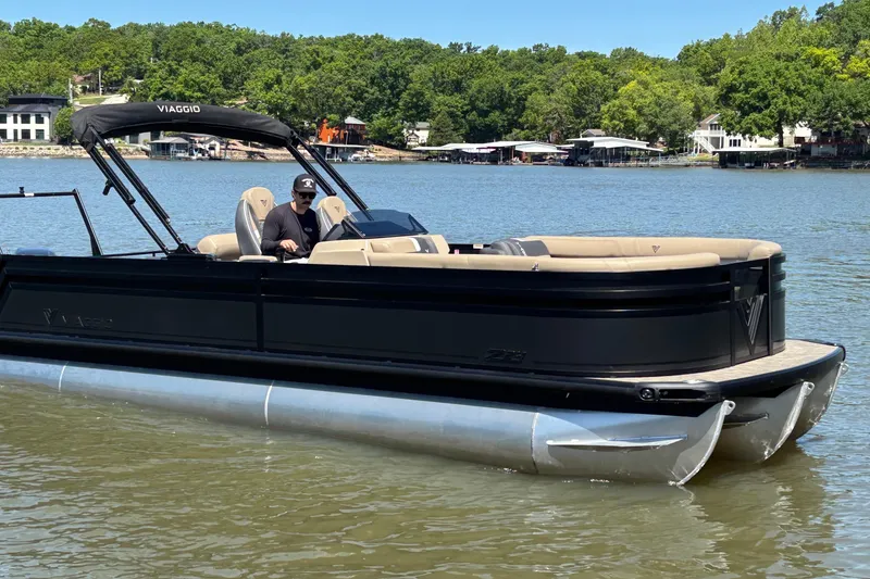 Slide: The Image of 2026 Viaggio Z24U pontoon boat on a lake, featuring sleek black design and comfortable seating. - 2