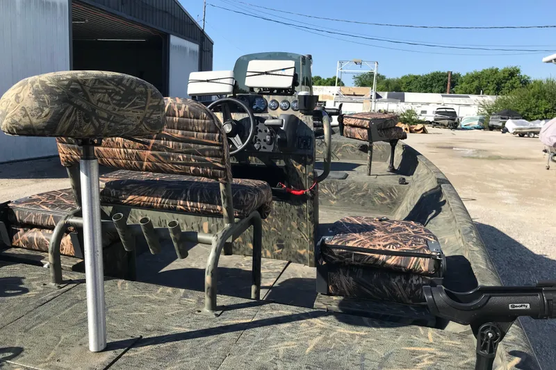 Slide: The Image of 2015 War Eagle 961 Blackhawk boat with camo seats and steering console in a sunny outdoor setting. - 4