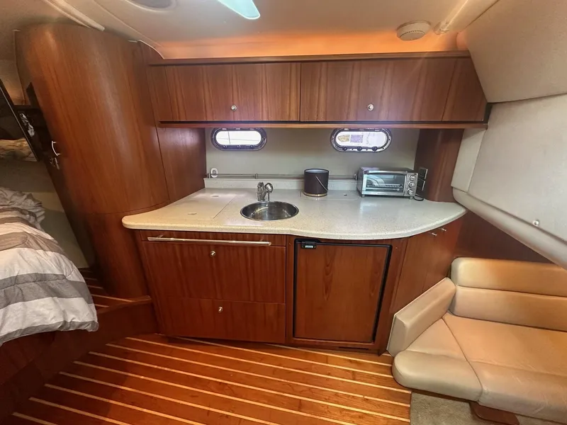 Slide: The Image of 2008 Tiara Yachts 3500 Sovran interior with kitchenette, featuring wood cabinetry and compact appliances. - 13