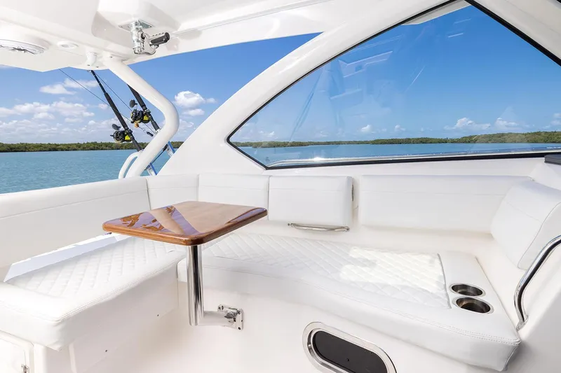 Slide: The Image of Manufacturer Provided Image: 2025 Pursuit OS 325 Offshore boat interior with white seating and wooden table. - 12