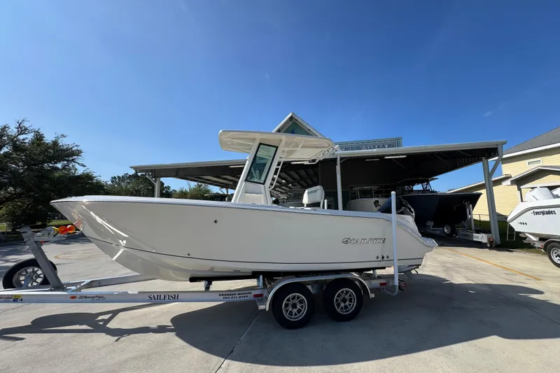The Image of 2026 Sailfish 232 CC boat on trailer, parked outdoors under clear blue sky. - 1