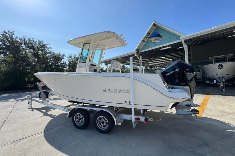 Slide: The Image of 2026 Sailfish 232 CC boat on trailer, parked outside a marina with trees in the background. - 14