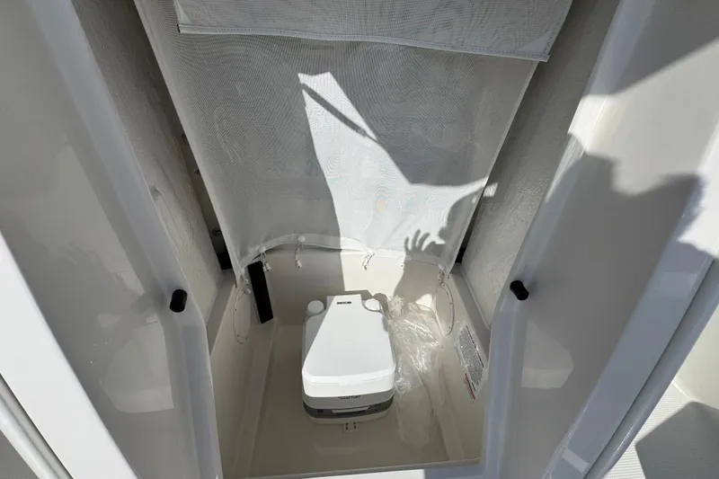 Slide: The Image of Portable toilet inside 2026 Sailfish 232 CC boat cabin, featuring compact design and privacy curtain. - 23