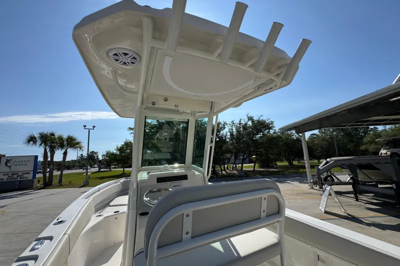 Slide: The Image of 2026 Sailfish 232 CC boat interior with T-top and seating, parked outdoors. - 32