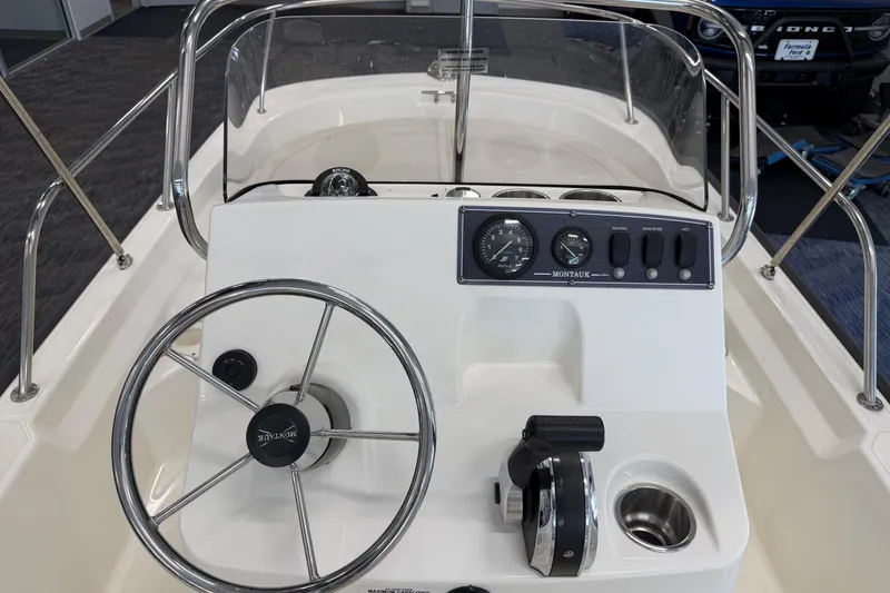 Slide: The Image of 2021 Boston Whaler 150 Montauk boat console with steering wheel and control panel. - 11