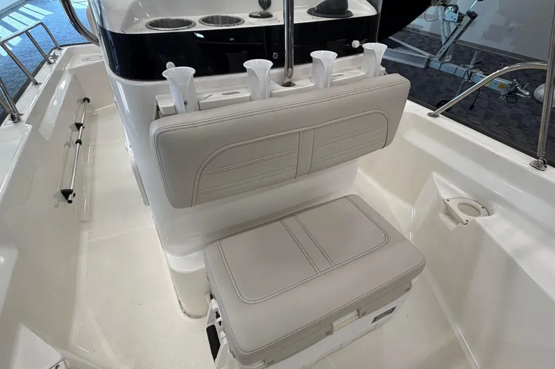 Slide: The Image of 2021 Boston Whaler 150 Montauk boat interior with cushioned seating and rod holders. - 13