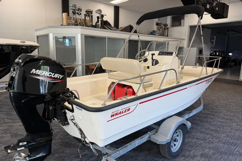 Slide: The Image of 2021 Boston Whaler 150 Montauk boat with Mercury engine on trailer in showroom. - 4