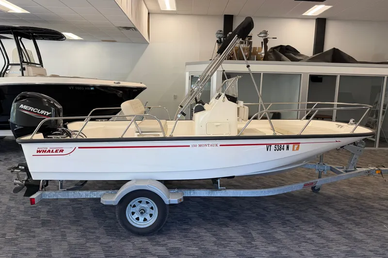 Slide: The Image of 2021 Boston Whaler 150 Montauk boat on trailer, displayed indoors with Mercury engine. - 5