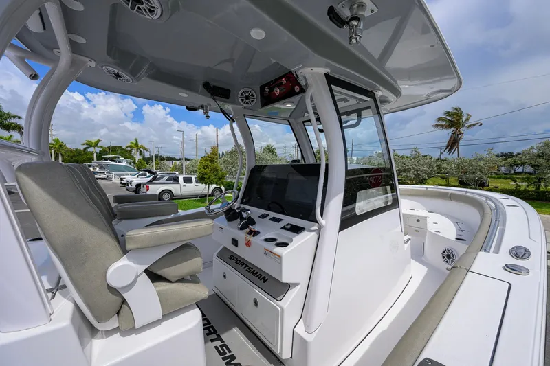 Slide: The Image of 2023 Sportsman Open 302 Center Console boat interior with helm and seating, under a clear sky. - 17