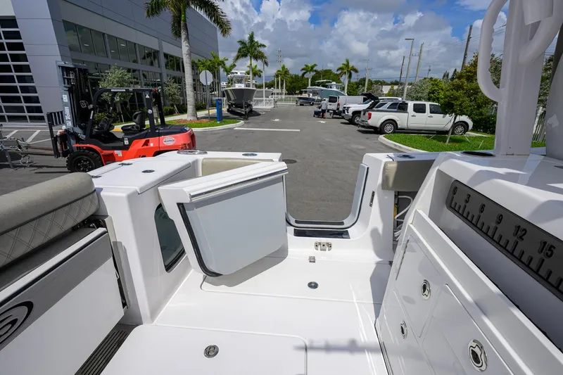 Slide: The Image of 2023 Sportsman Open 302 Center Console boat interior at a dealership with parked vehicles. - 30