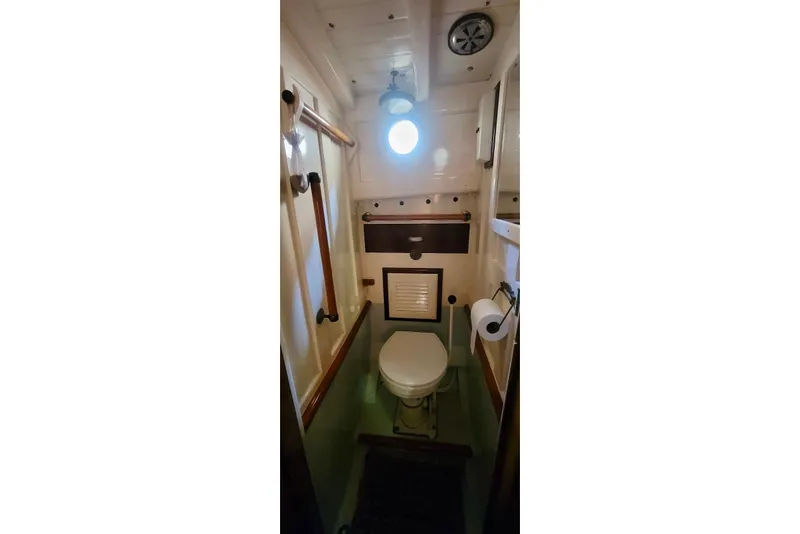 Slide: The Image of 1936 Freeman 37 boat bathroom with porthole, toilet, and wooden accents. - 11