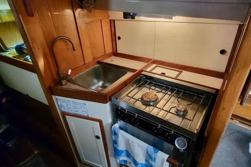 Slide: The Image of Compact kitchen area in a 1936 Freeman 37 boat, featuring a sink and gas stove. - 9