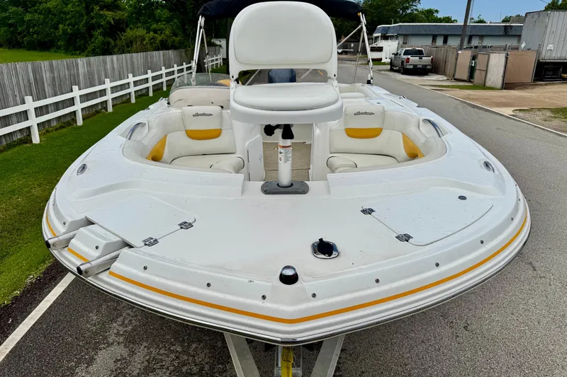 Slide: The Image of 2014 Hurricane SunDeck Sport 203 OB boat with white and yellow seating, parked on a street. - 6