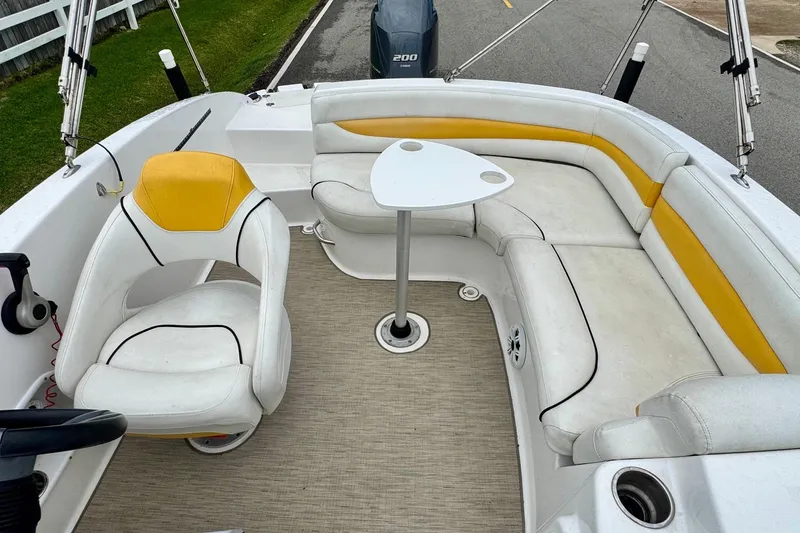 Slide: The Image of 2014 Hurricane SunDeck Sport 203 OB boat interior with white and yellow seating and a small table. - 7