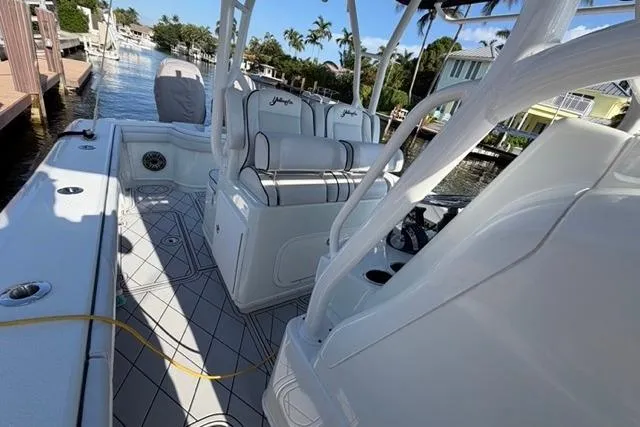 Slide: The Image of 2019 Yellowfin 32 Offshore boat interior with seating and console, docked by waterfront homes. - 11